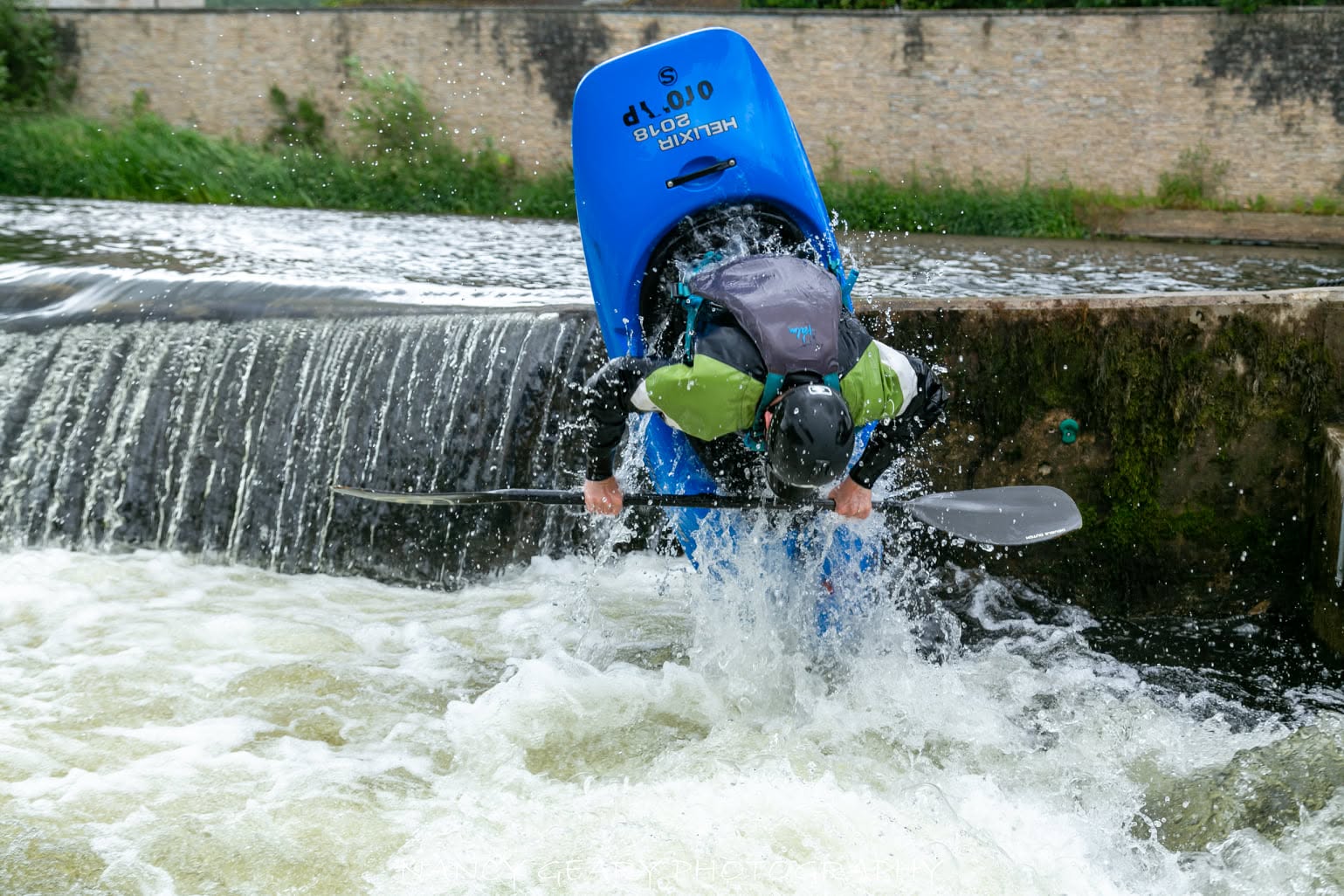 A freestyle paddler performing a vertical move at The Fishboxes in Clonmel, Ireland